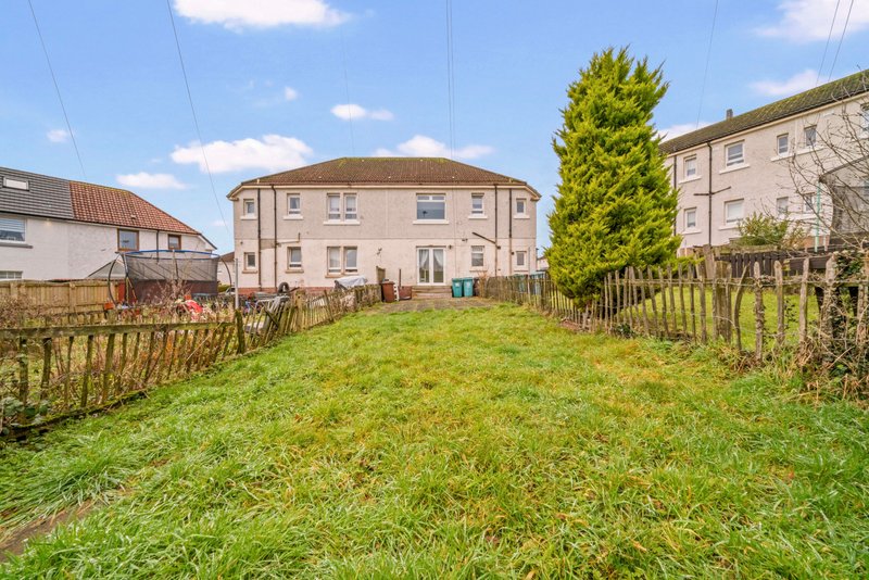 Large detached house with garden, wooden fencing and green lawn viewed from rear