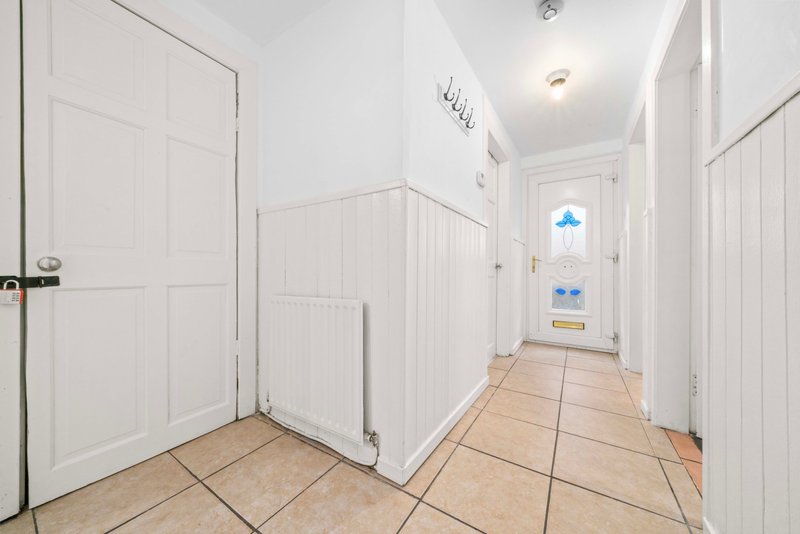 Hallway with white doors, tiled flooring, radiator and natural light from window