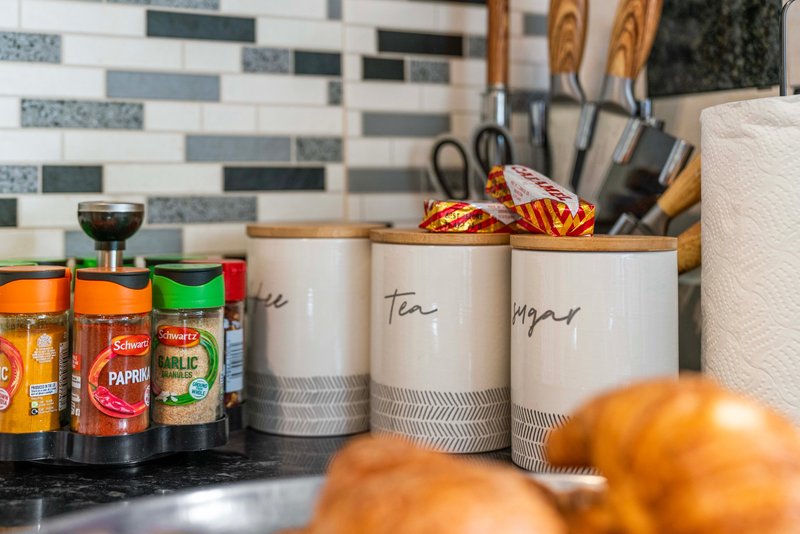 Kitchen counter with branded spice jars, labeled storage containers, and fresh oranges