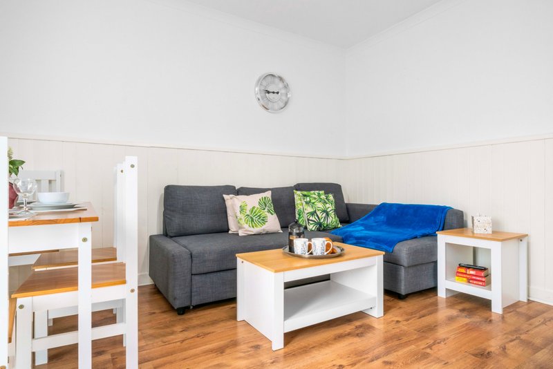 Modern living room with grey corner sofa, white coffee table, wooden flooring and potted plants