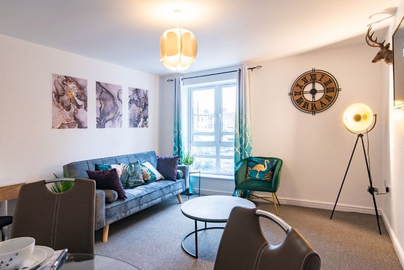 Modern living room with blue sofa, green armchair, round coffee table and floor lamp