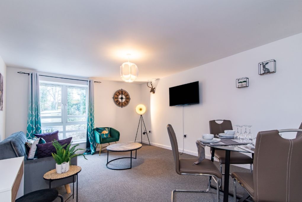 Modern living room with sofa, dining table, wall-mounted TV and glass doors to garden