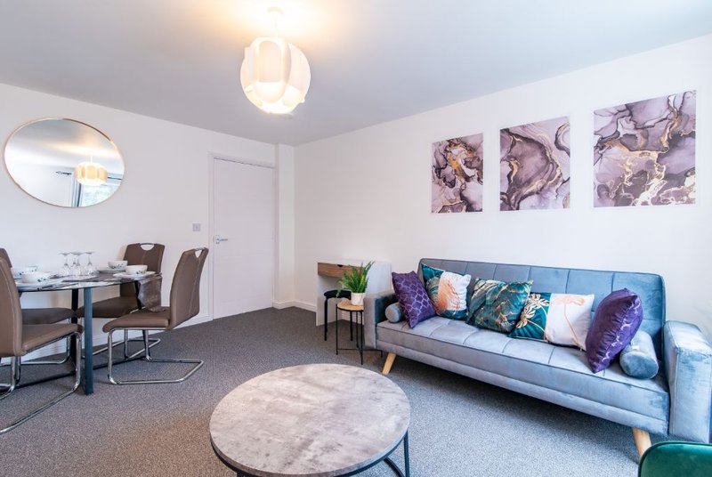 Modern living room with blue sofa, dining table, round rug and wall art