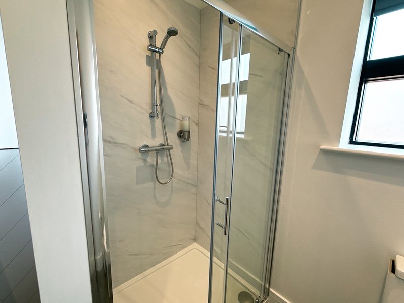 Modern bathroom with enclosed shower cubicle, rainfall showerhead and tiled walls