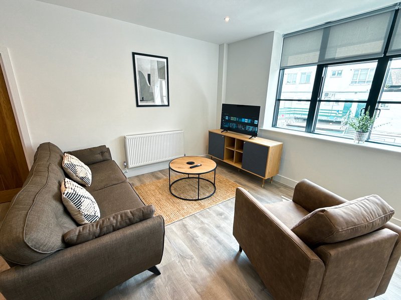Modern living room with grey sofas, round coffee table, TV stand and large windows