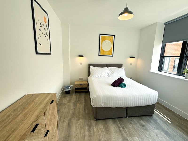 Modern bedroom with double bed, wooden flooring, pendant light and framed wall art