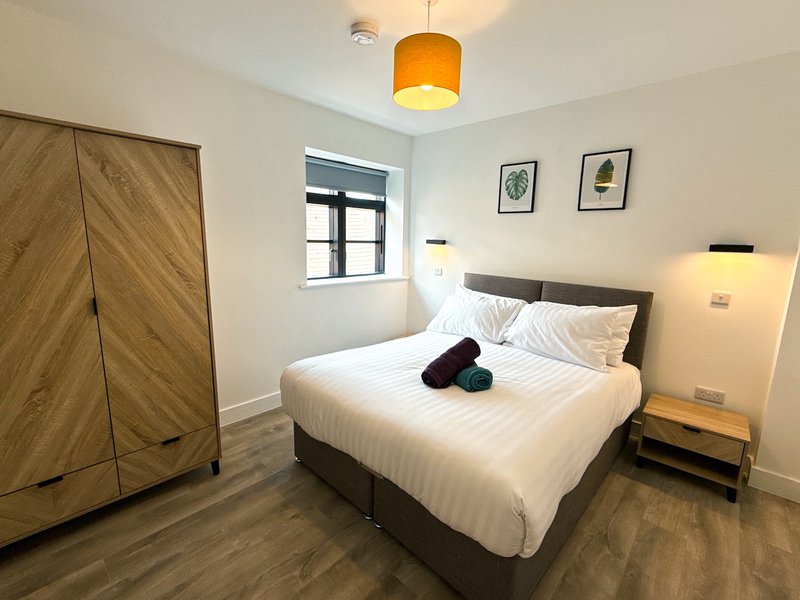 Modern bedroom with double bed, wooden wardrobe, pendant light and framed wall art