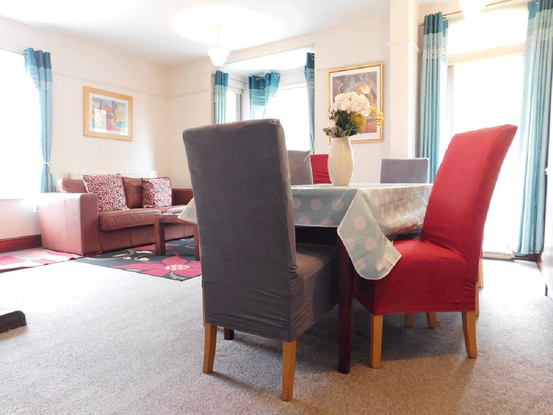 Spacious living room with dining table, upholstered chairs, sofa, and framed wall art
