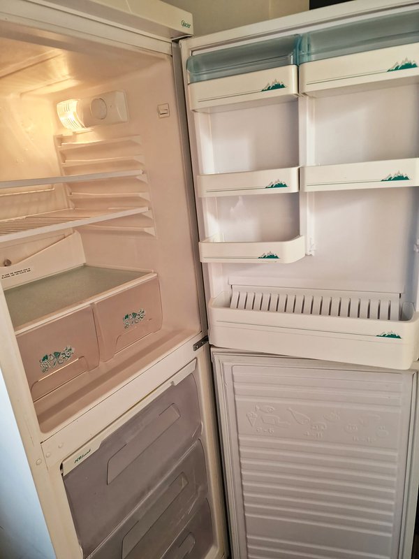 Open empty refrigerator with white shelves and freezer compartment below