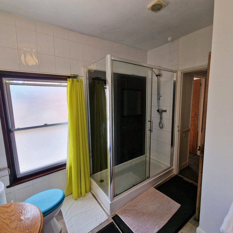 Bathroom with shower enclosure, yellow curtain, toilet, and tiled walls