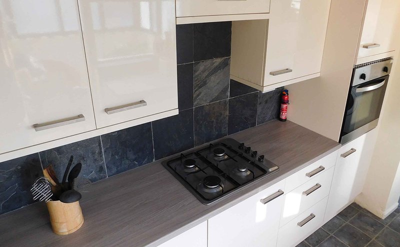 Modern kitchen with white cabinets, black gas hob, dark tile splashback and wooden countertop