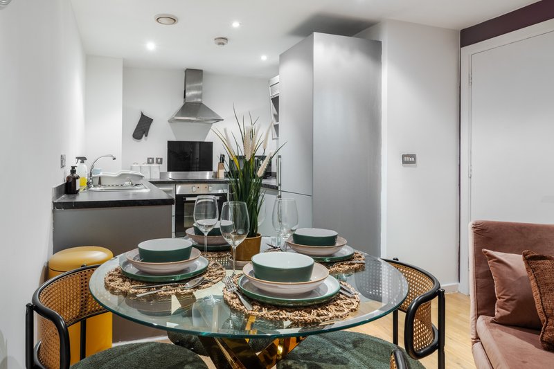 Modern kitchen-diner with round glass table, place settings, and fitted appliances