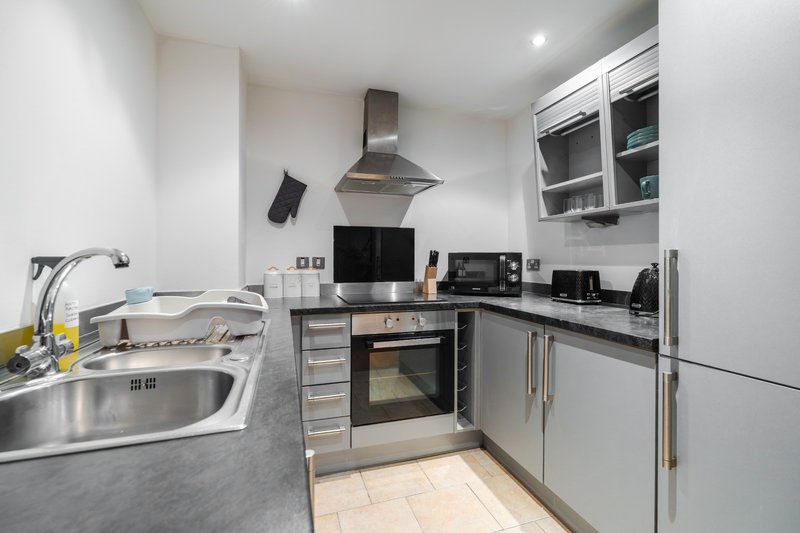 Modern kitchen with stainless steel appliances, granite worktops, and integrated oven