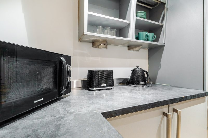 Modern kitchen with microwave, toaster, kettle and wall-mounted cabinets