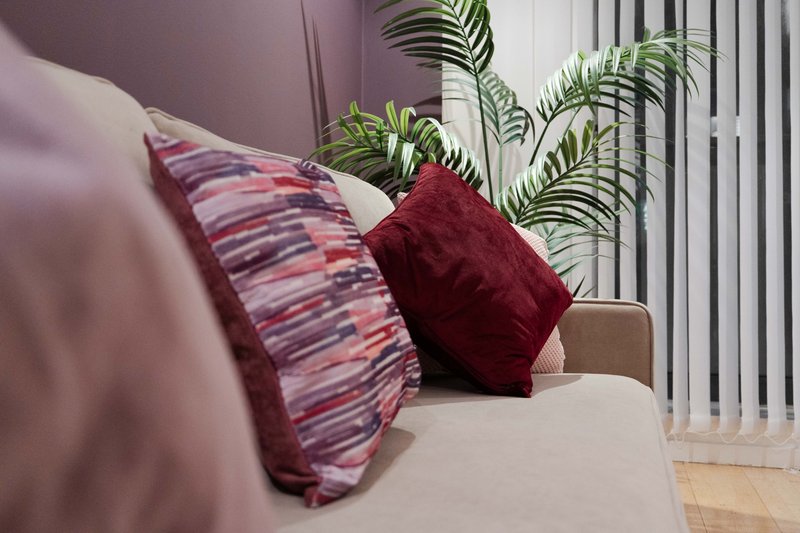 Modern living room with cream sofa, decorative pillows, potted plants and vertical blinds