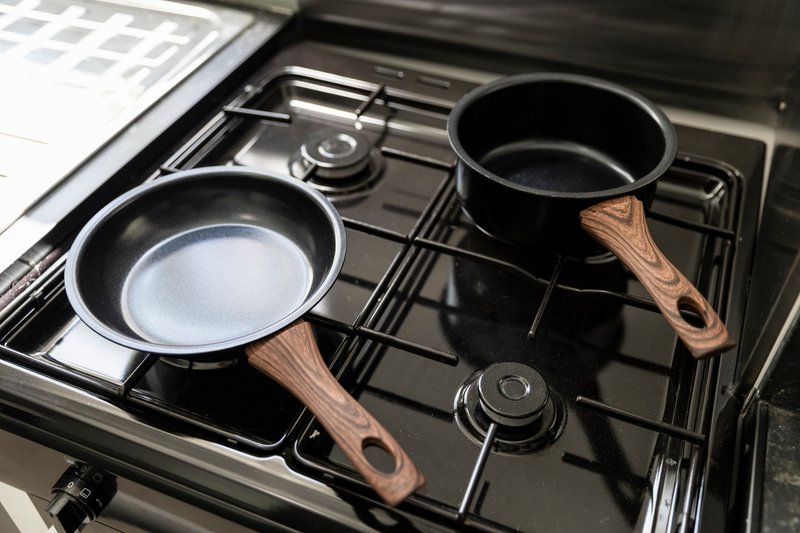 Gas cooktop with two non-stick pans with wooden handles and burner controls