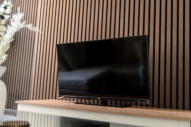 Modern living room with flat-screen TV mounted on wooden slat wall panel