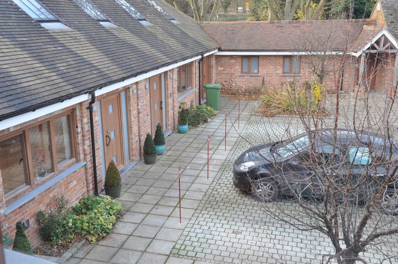 Brick courtyard with paved ground, potted plants, parked motorcycle and bare trees