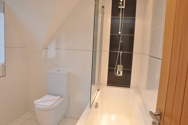 Modern bathroom with toilet, walk-in shower enclosure, and wooden door