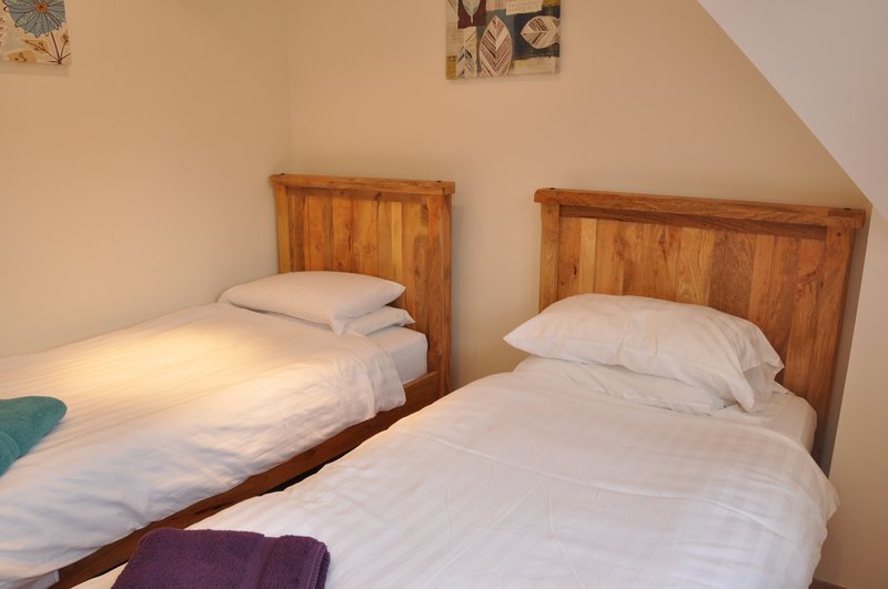 Twin bedroom with two wooden-framed beds, white bedding, and sloped ceiling