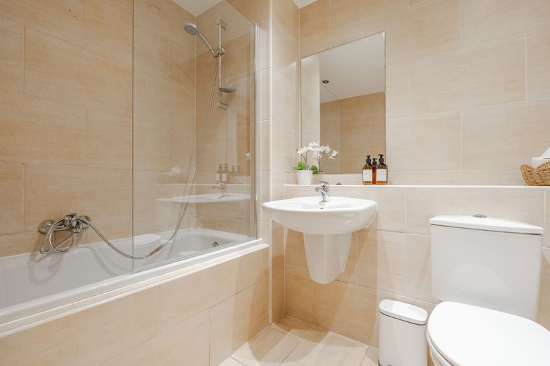 Modern bathroom with bathtub, glass shower screen, pedestal sink and toilet