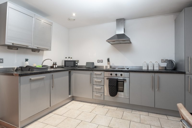 Modern kitchen with grey cabinetry, stainless steel appliances, dark countertops and tiled flooring