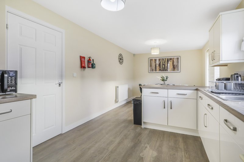 Modern kitchen with white cabinetry, gray wood-effect flooring, and cream walls