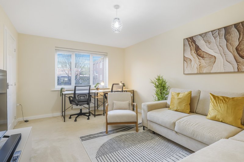 Bright living room with cream sofa, desk chair, armchair, and abstract wall art