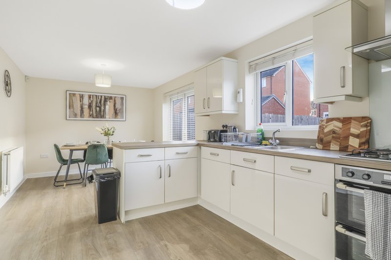 Modern kitchen with white cabinetry, stainless steel appliances, wooden flooring and dining area.
