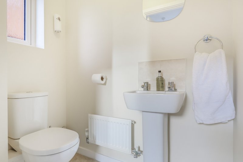 Clean white bathroom with toilet, pedestal sink, radiator and towel rail