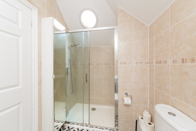 Modern bathroom with walk-in shower enclosure, toilet, and circular ceiling light