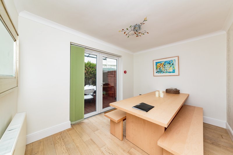 Light dining room with wooden table, bench seating, and glass doors leading to garden