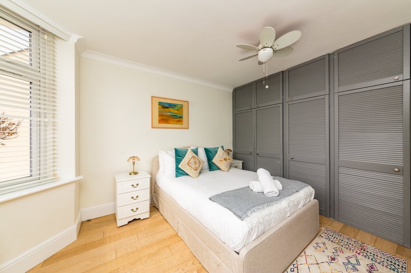 Bedroom with double bed, grey fitted wardrobes, wooden floor and ceiling fan