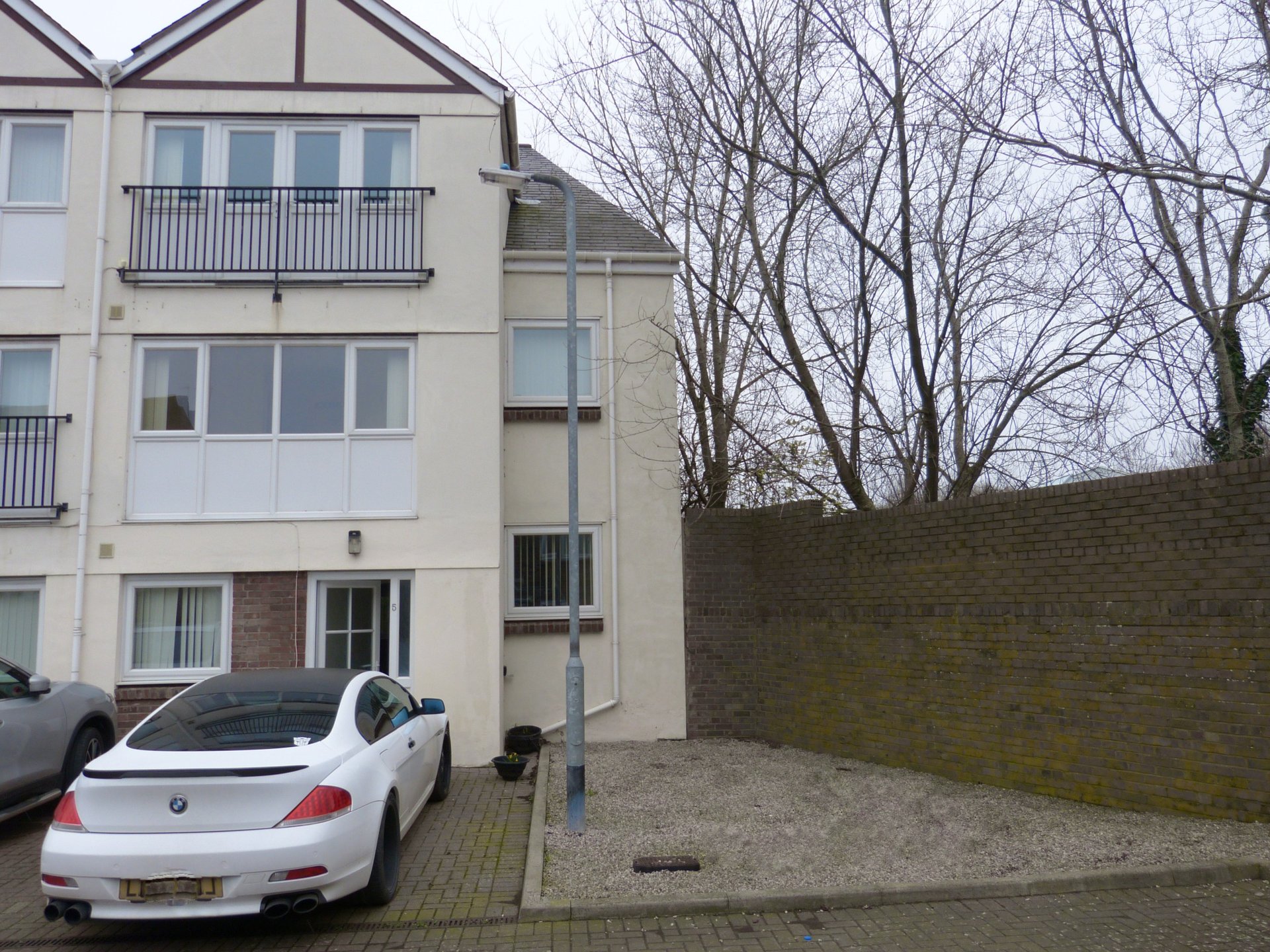 Modern multi-story residential building with parking area and brick wall exterior