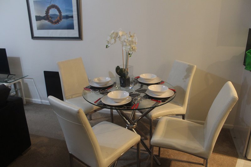 Dining area with round table, place settings, white chairs and floral centerpiece