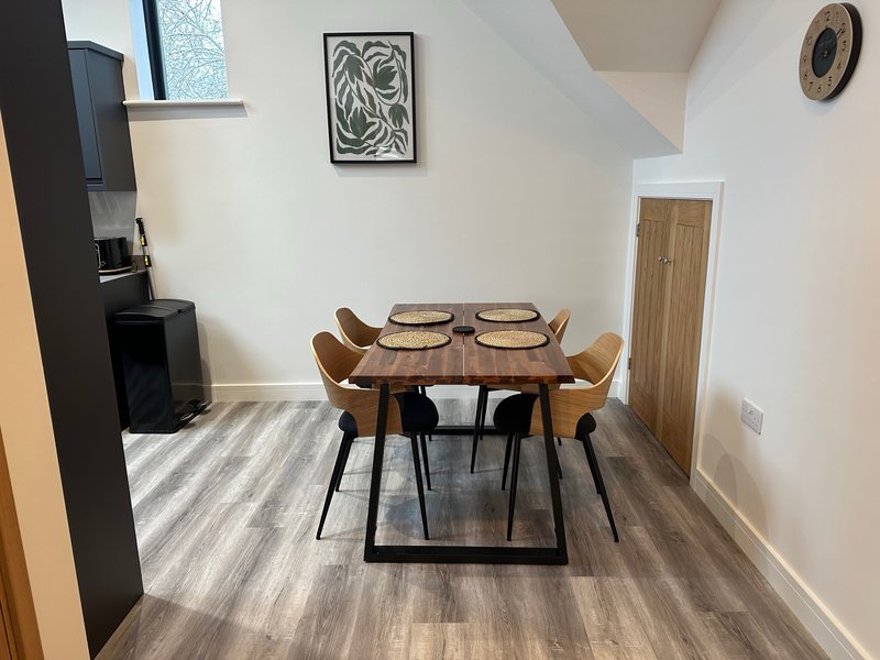 Dining area with wooden table, four chairs, striped rug and wall art