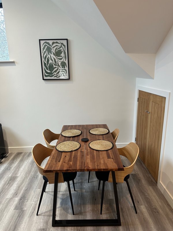 Modern dining area with wooden table, four chairs, and framed wall art