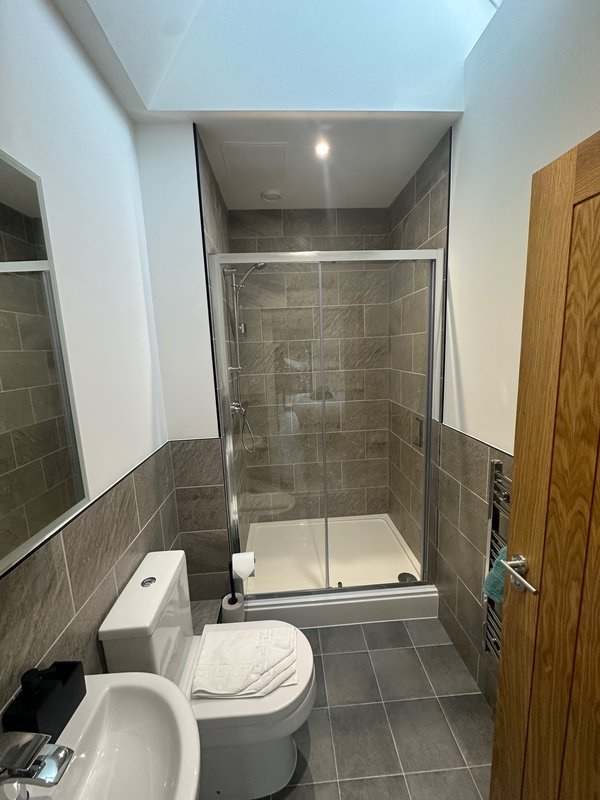 Modern bathroom with walk-in shower, toilet, and grey tile flooring