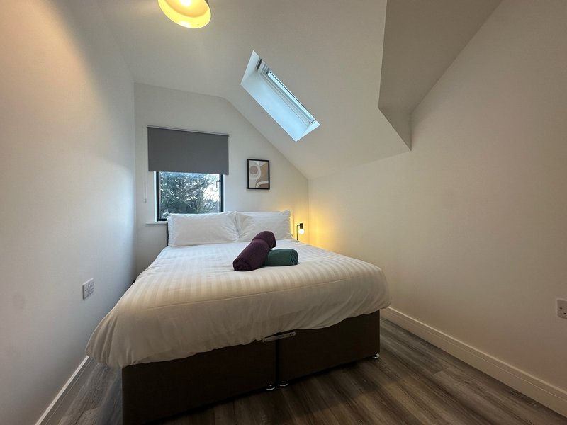 Bright attic bedroom with double bed, skylight window, and bedside lamps