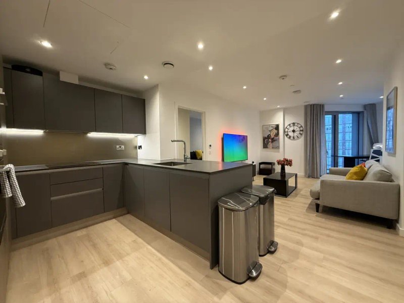 Modern open-plan kitchen and living area with dark cabinetry, island, and seating area