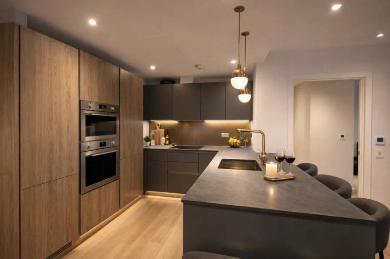 Modern kitchen with dark cabinetry, wooden accents, island countertop and pendant lighting