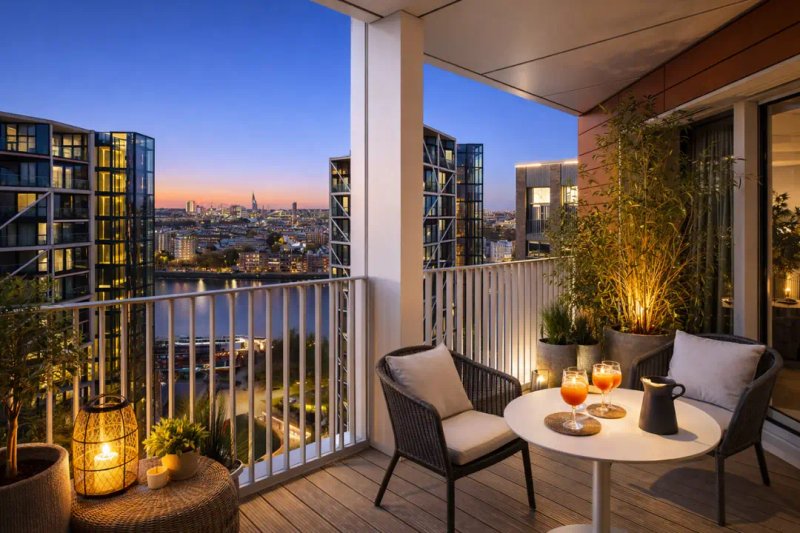 Balcony seating area at dusk with city skyline view, plants, and candles