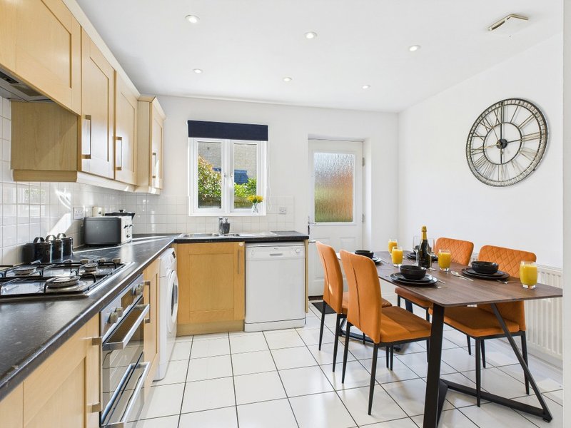 Modern kitchen-diner with light wood cabinets, black countertops, dining table and orange chairs