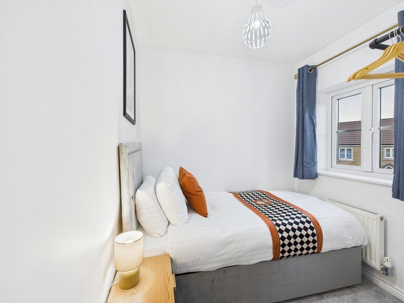 Bright bedroom with double bed, white bedding, decorative pillows and pendant light