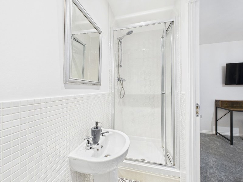 Modern bathroom with white subway tile, round sink, mirror, and glass shower enclosure