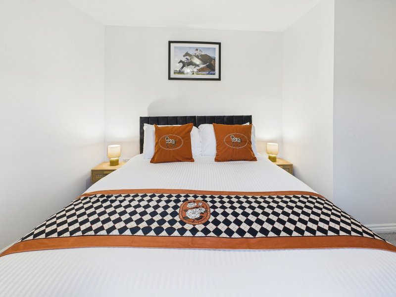 Bedroom with double bed, orange and black geometric bedding, wooden headboard and side tables with lamps