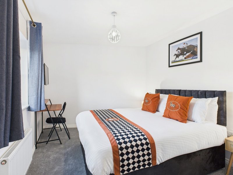 Modern bedroom with double bed, orange and black geometric bedding, wall art, pendant light