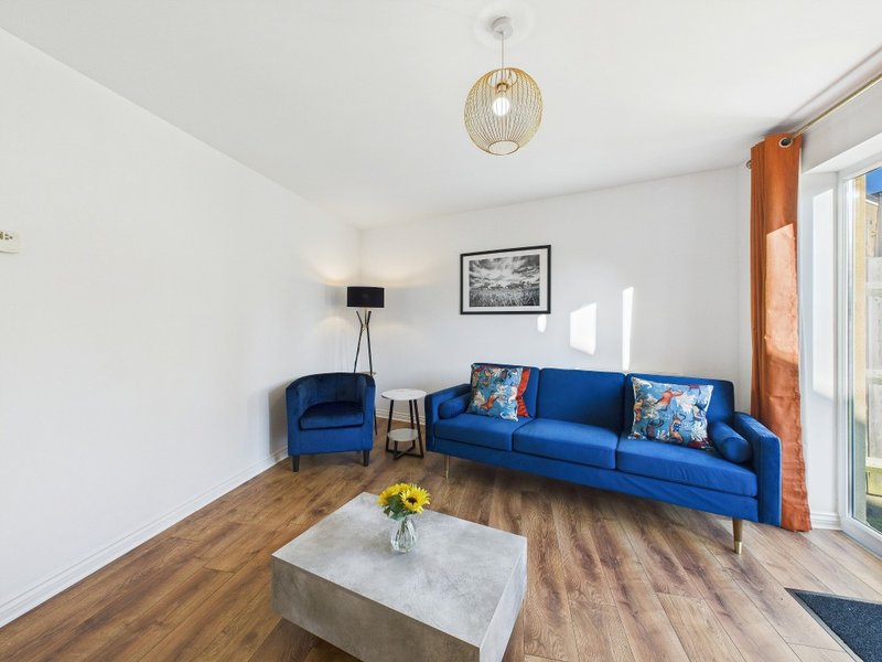 Modern living room with blue sofa, armchair, wooden floors and glass doors