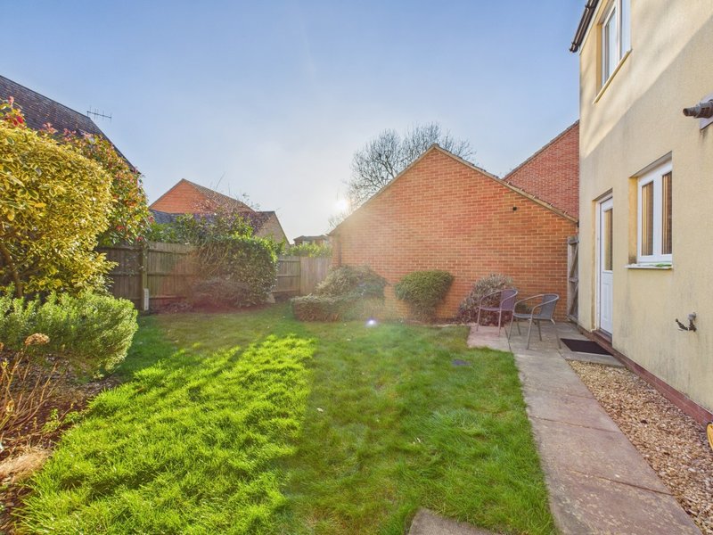 Rear garden with lawn, patio, brick house and neighboring properties visible