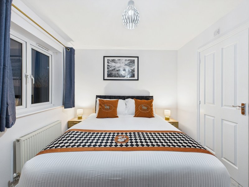 Bright modern bedroom with double bed, orange cushions, patterned bedding and pendant light fixture